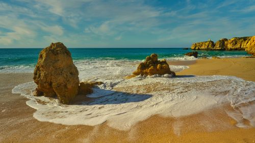 Free Beautiful beach scene with rugged rock formations and gentle waves crashing on the shore. Stock Photo