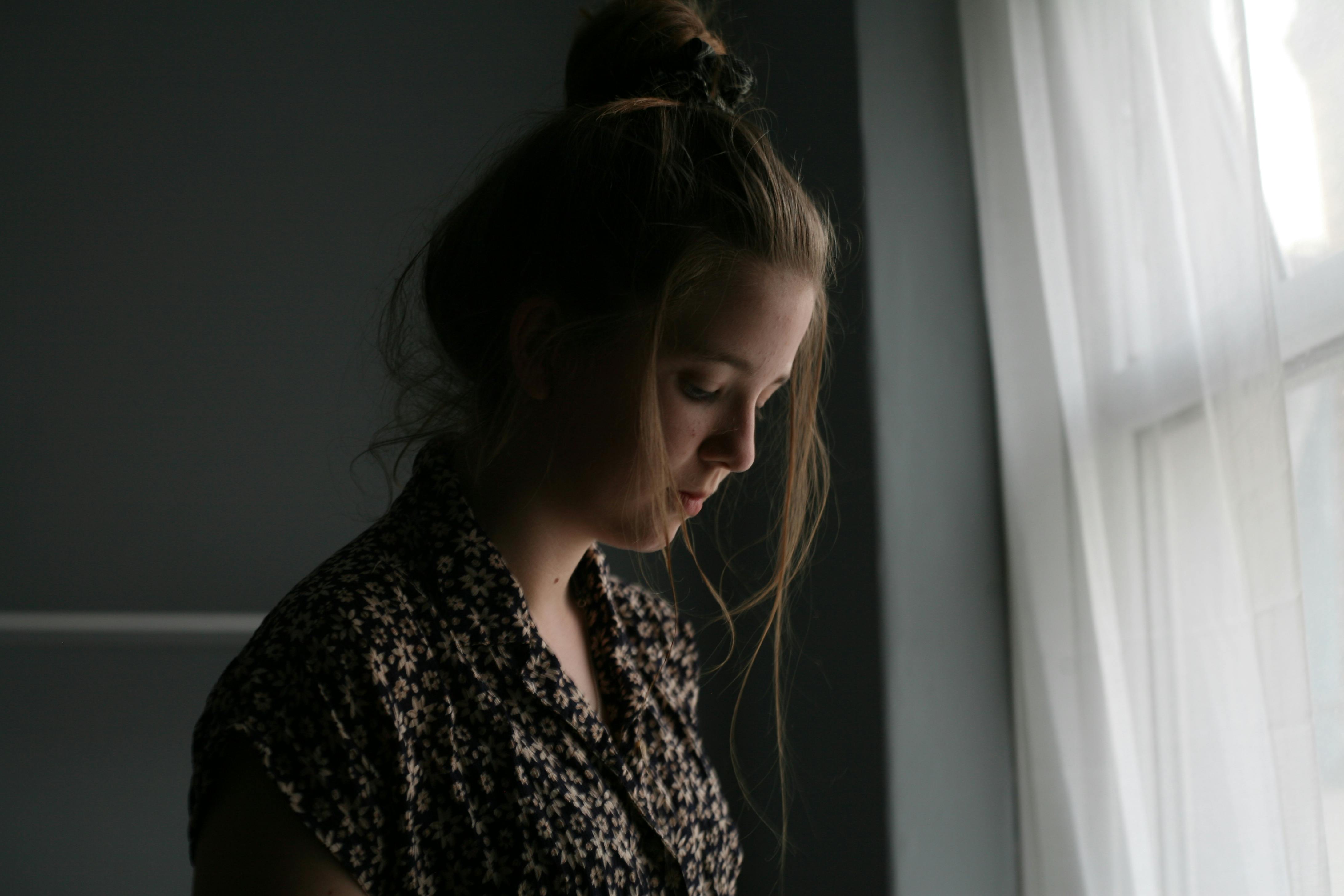 Traurige Frau, die neben dem Fenster steht. | Foto: Pexels