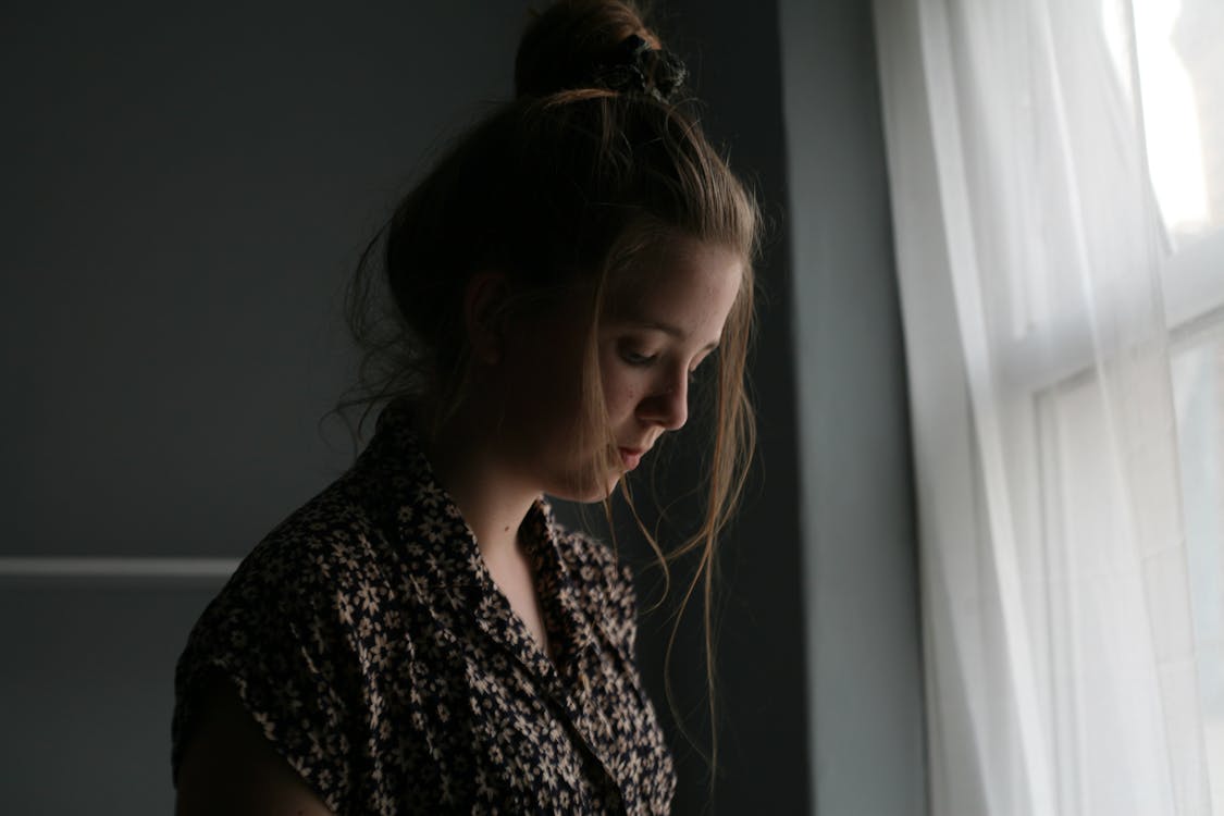 Woman Standing Beside Window Curtain