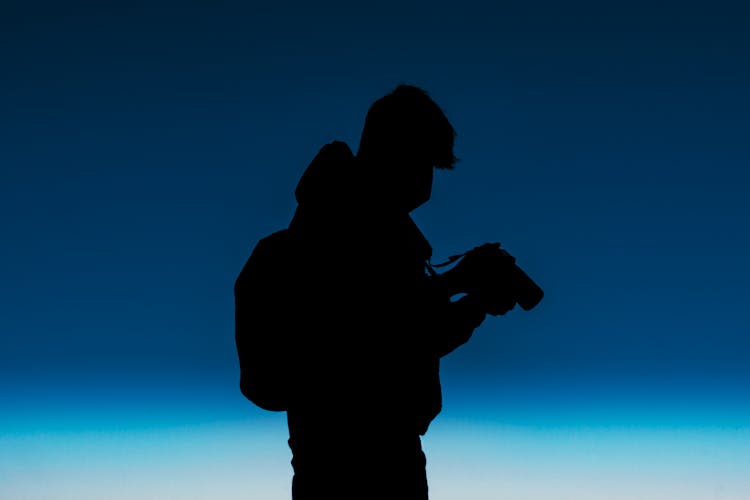 Silhouette Of A Person Holding A Camera 