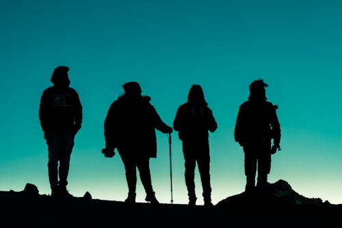 Silhouettes of Group of People on Mountain During Sunset