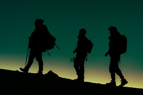 Silhouettes of Group of People on Mountain During Sunset