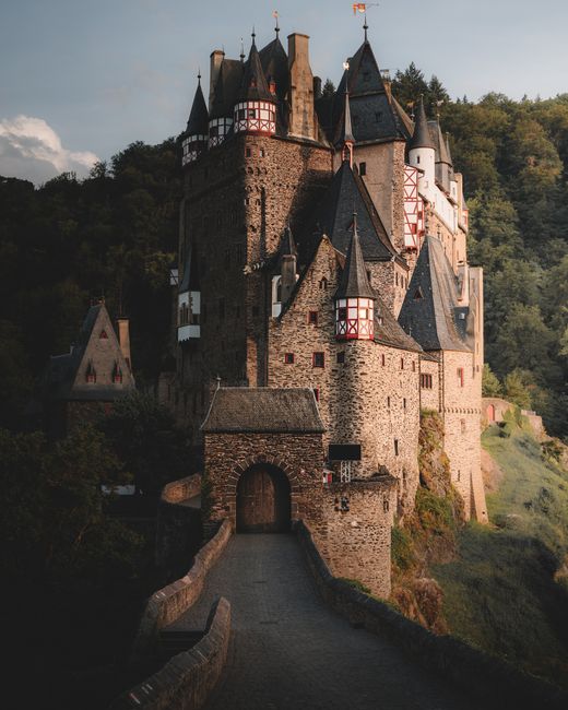 Explore this stunning medieval castle in Germany, surrounded by lush forest, captured at dusk.