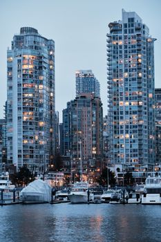 Cityscape showcasing Vancouver skyline with yachts moored in the marina at dusk.