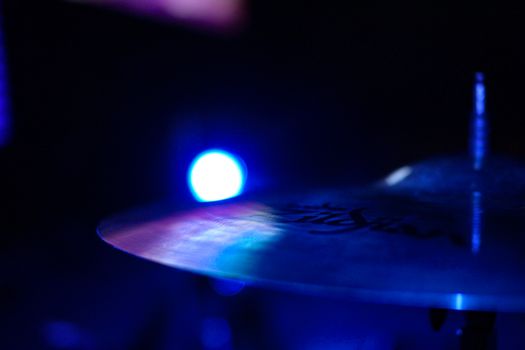 戏剧性的特写镜头中，鼓钹在蓝色照明下从黑暗背景中突出