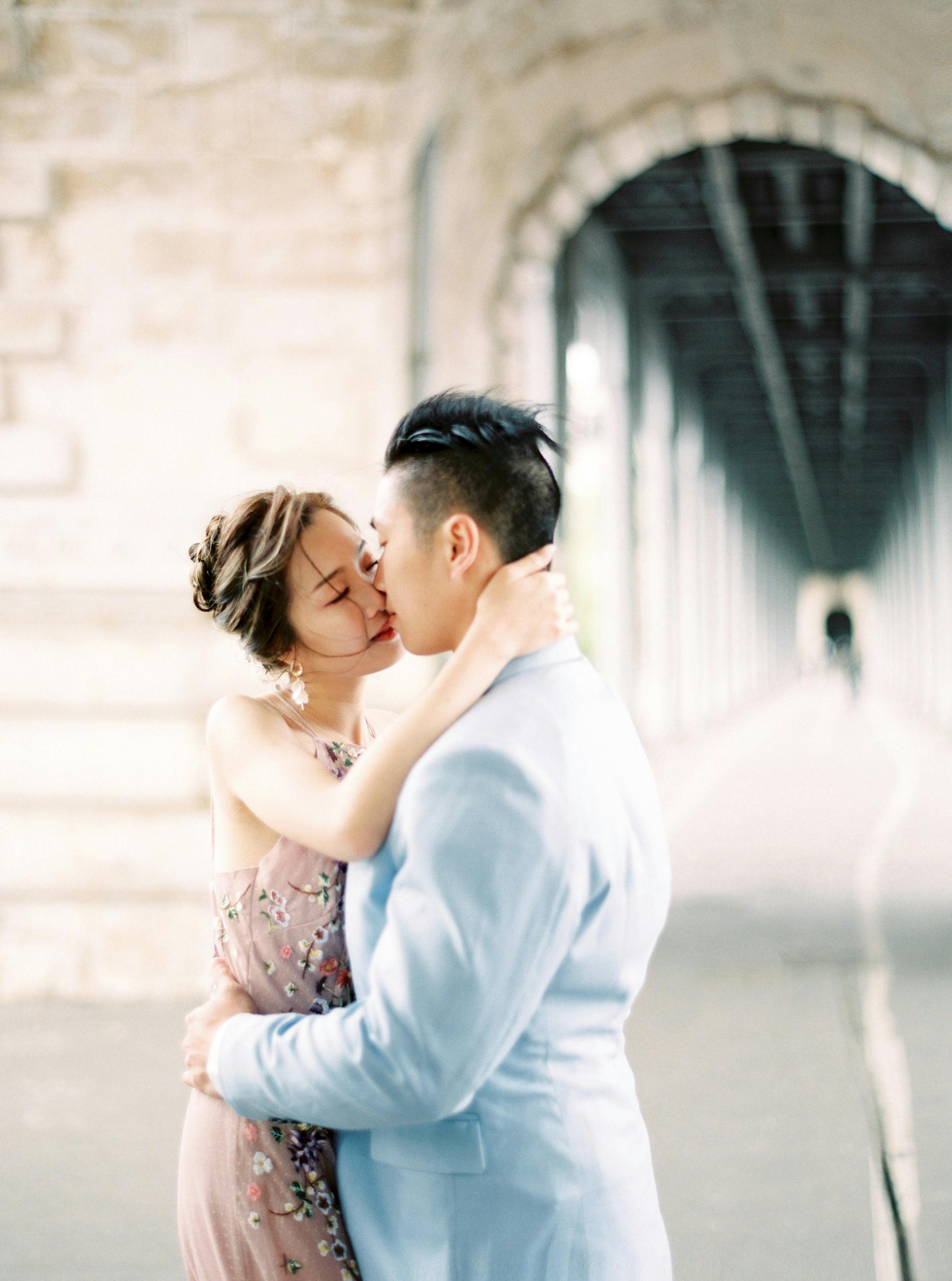 A loving couple shares a kiss in a beautiful urban archway, capturing a moment of romance and connection.