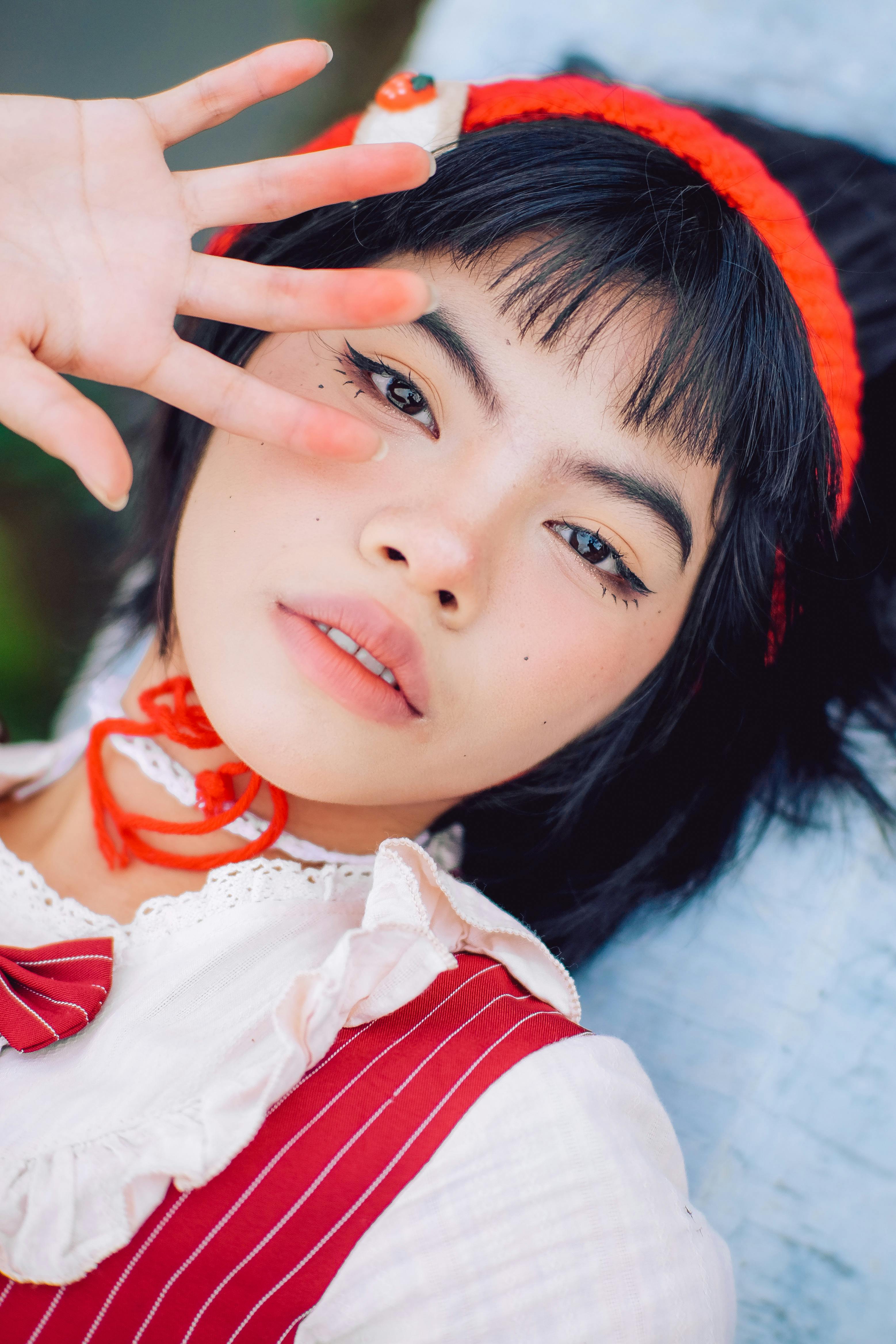 A captivating portrait of a teenage girl in cosplay attire, posing creatively with a red headband.