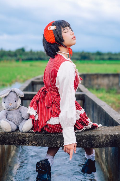 Girl in Traditional Costume Sitting Outdoors with Toy