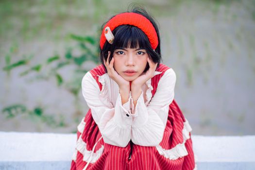 A young woman poses outdoors in a red and white dress with a matching headband.