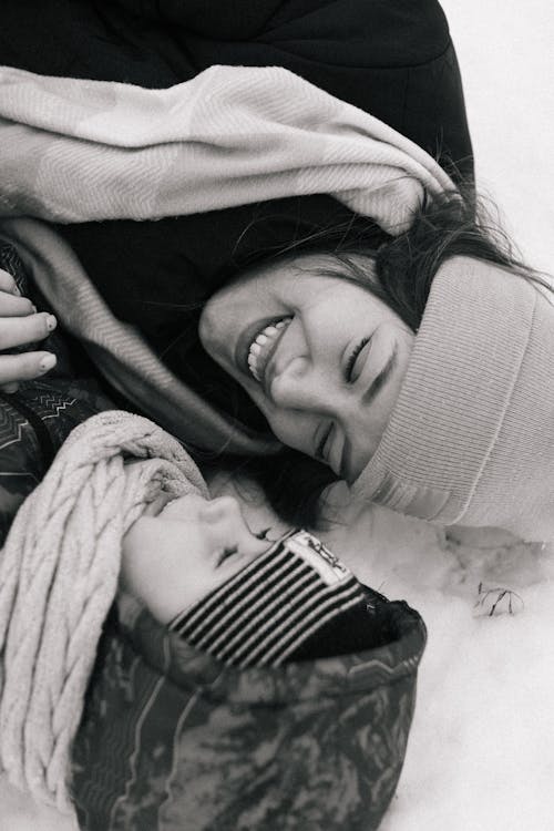 Smiling Woman and Child Lying on Snow Ground