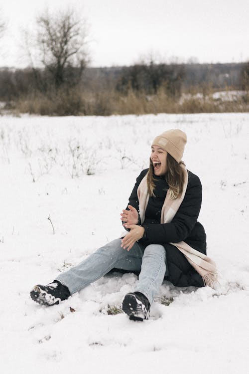 Smiling Woman Sitting on Snow Ground