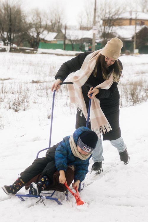 Smiling Woman with Child Riding Sled in Winter Countryside