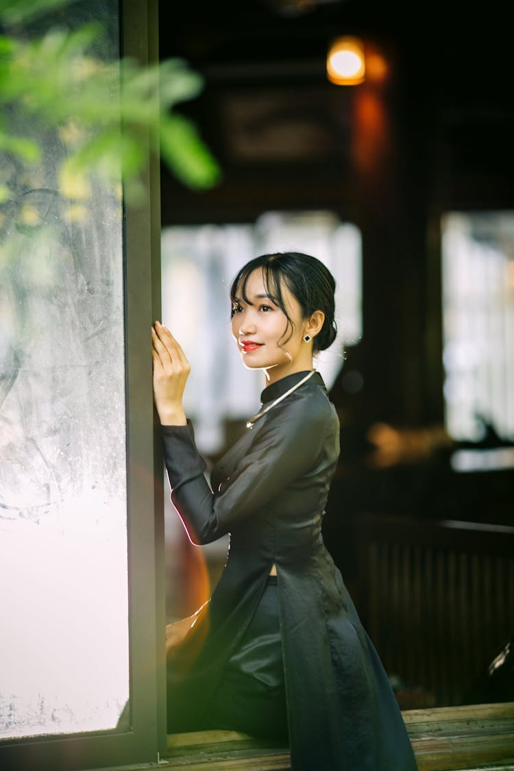 Smiling Woman In Black Dress Posing Near Wall