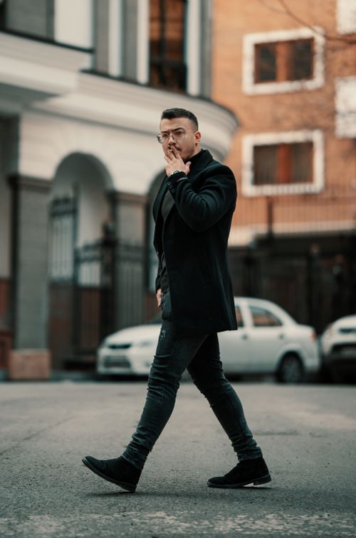 Free A fashionable man walks while smoking on an urban street in Tehran, Iran. Stock Photo