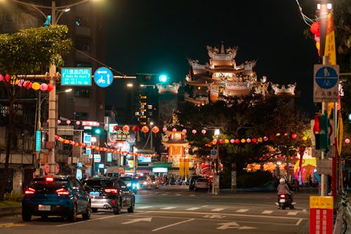 Moving Cars on the Road Near Buildings During Night Time