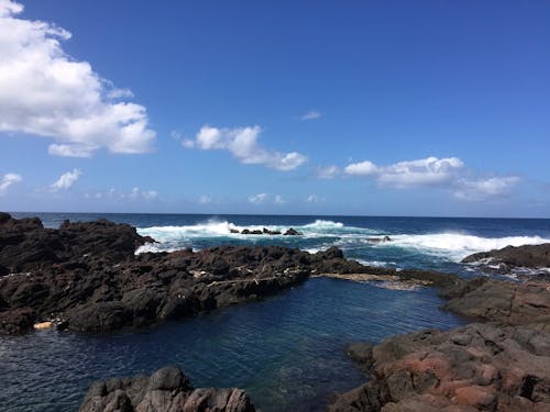 棕色岩石在海洋旁边，气泡波在蓝蓝的天空下