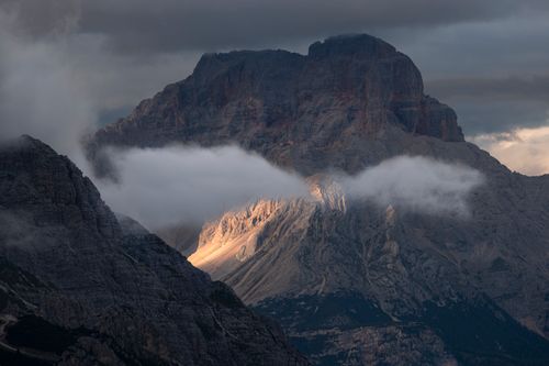 Free Moody mountain scene with clouds enveloping rugged peaks and diffuse sunlight. Stock Photo