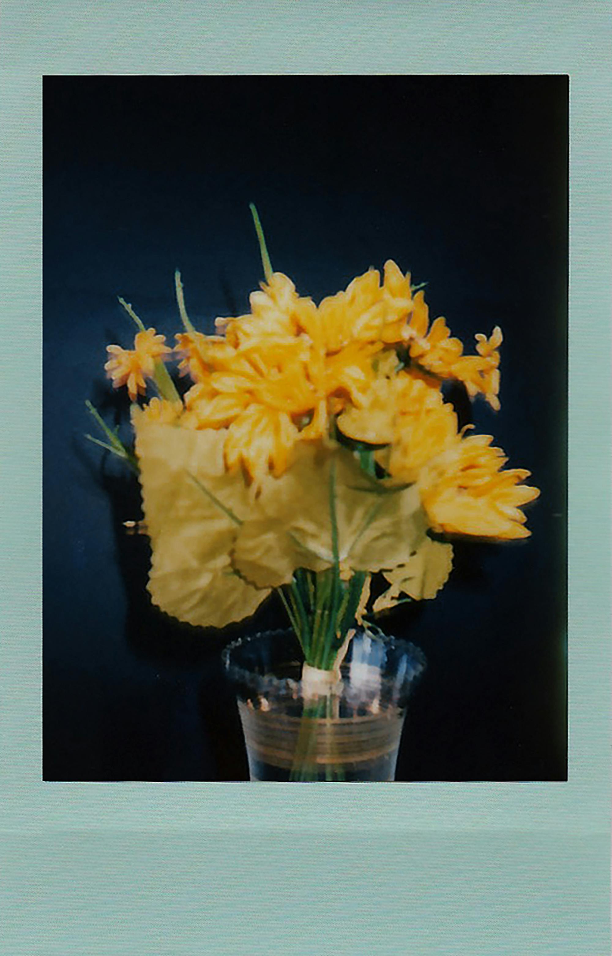 A bouquet of bright yellow flowers arranged in a clear vase with a dark backdrop, perfect for cheerful decor.