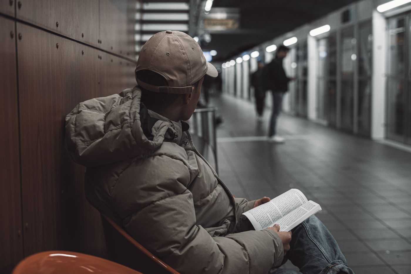 Homme lisant un livre sur un banc de station de métro