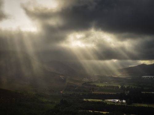 Free Captivating view of sunbeams piercing clouds over a lush valley in George, South Africa. Stock Photo