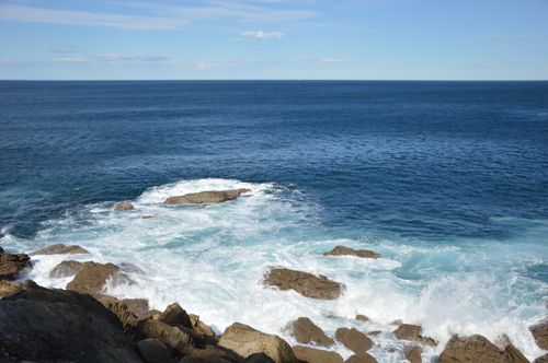 Free Experience the power of the ocean with waves crashing against a rugged rocky coastline under a clear blue sky. Stock Photo