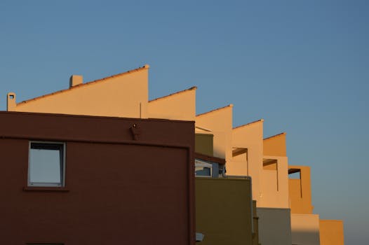 Contemporary terraced housing showcasing geometric design with distinct rooflines against a clear blue sky.