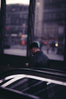 Man using smartphone on an escalator in Berlin during twilight, street photography