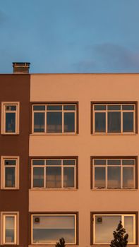 Vertical shot of a modern residential building facade with windows at sunset.