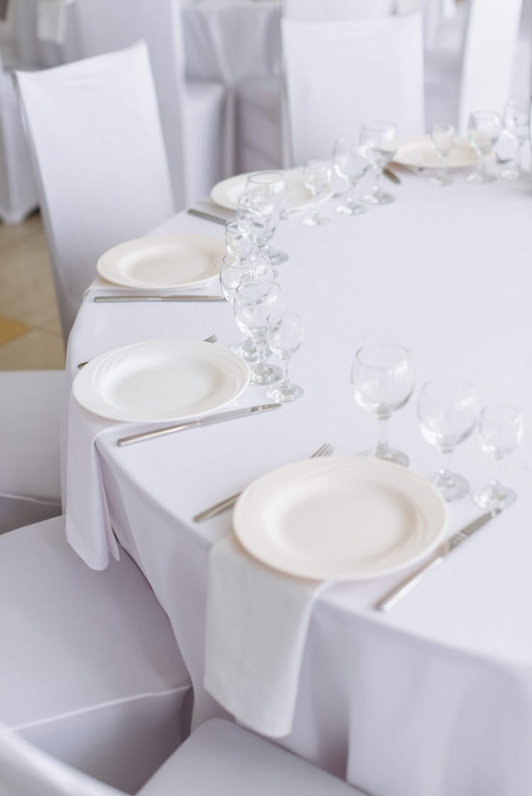 A White Table With Plates And Wine Glasses