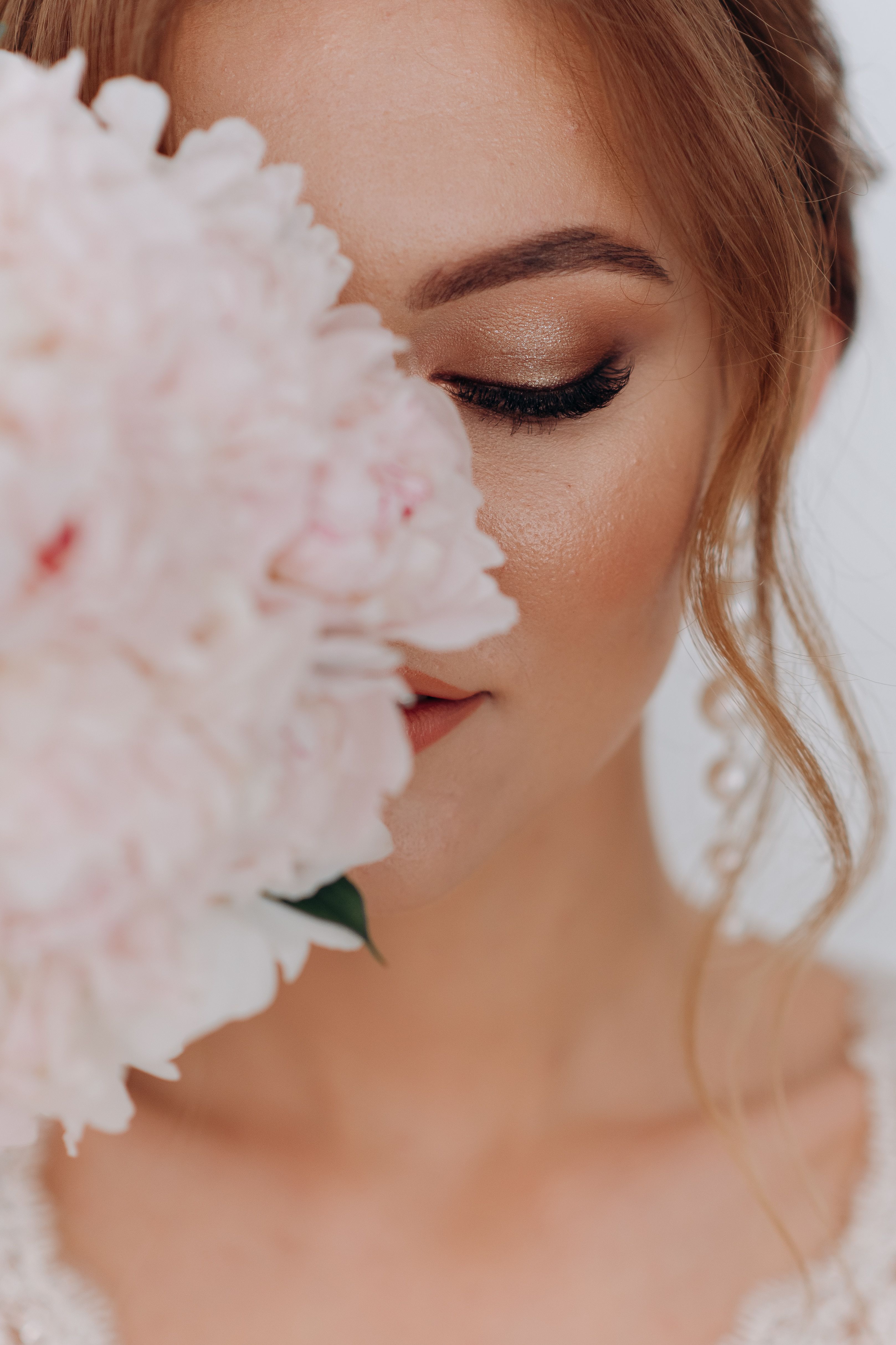 Close-up portrait of a woman embracing elegance and beauty with a peony flower.