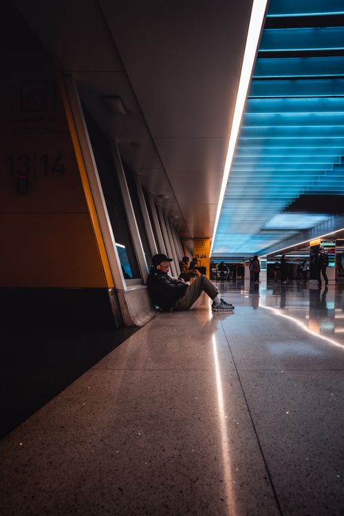 Free Modern airport terminal with people sitting and walking, featuring striking blue ceiling lights. Stock Photo