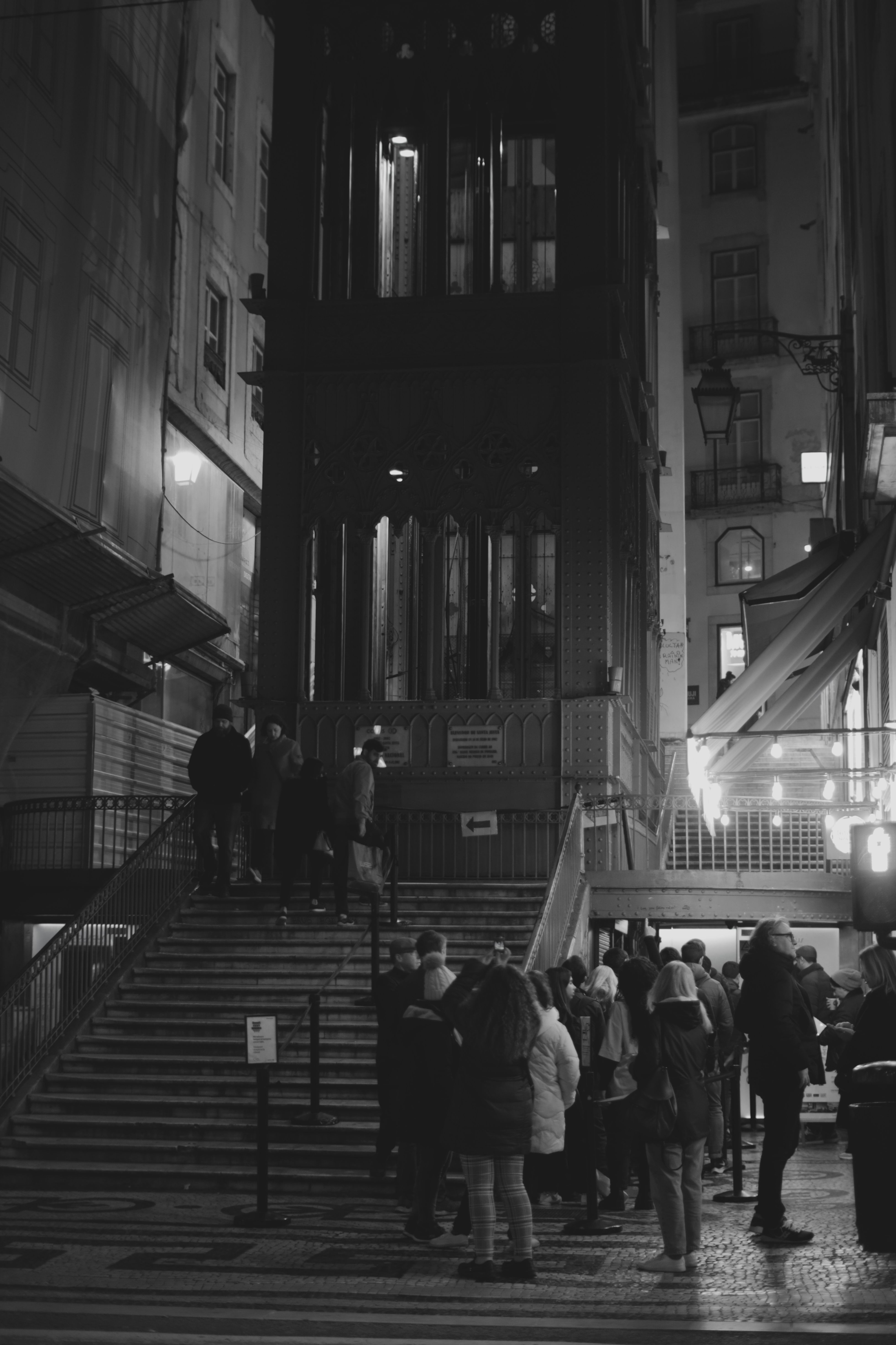 Gente esperando de noche en la vereda frente a un edificio antiguo