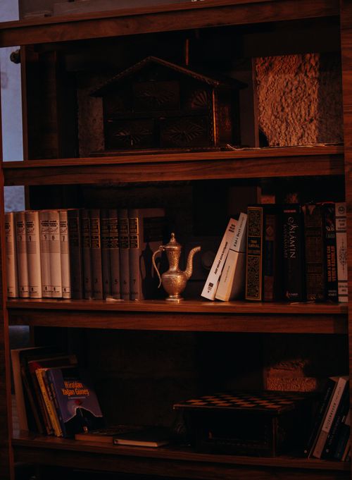 Free A warm, vintage bookshelf with antique books and a silver teapot, perfect for a cozy study. Stock Photo