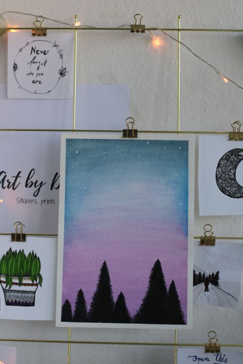 Free Artistic wall display featuring creative paintings and string lights for a cozy ambiance. Stock Photo