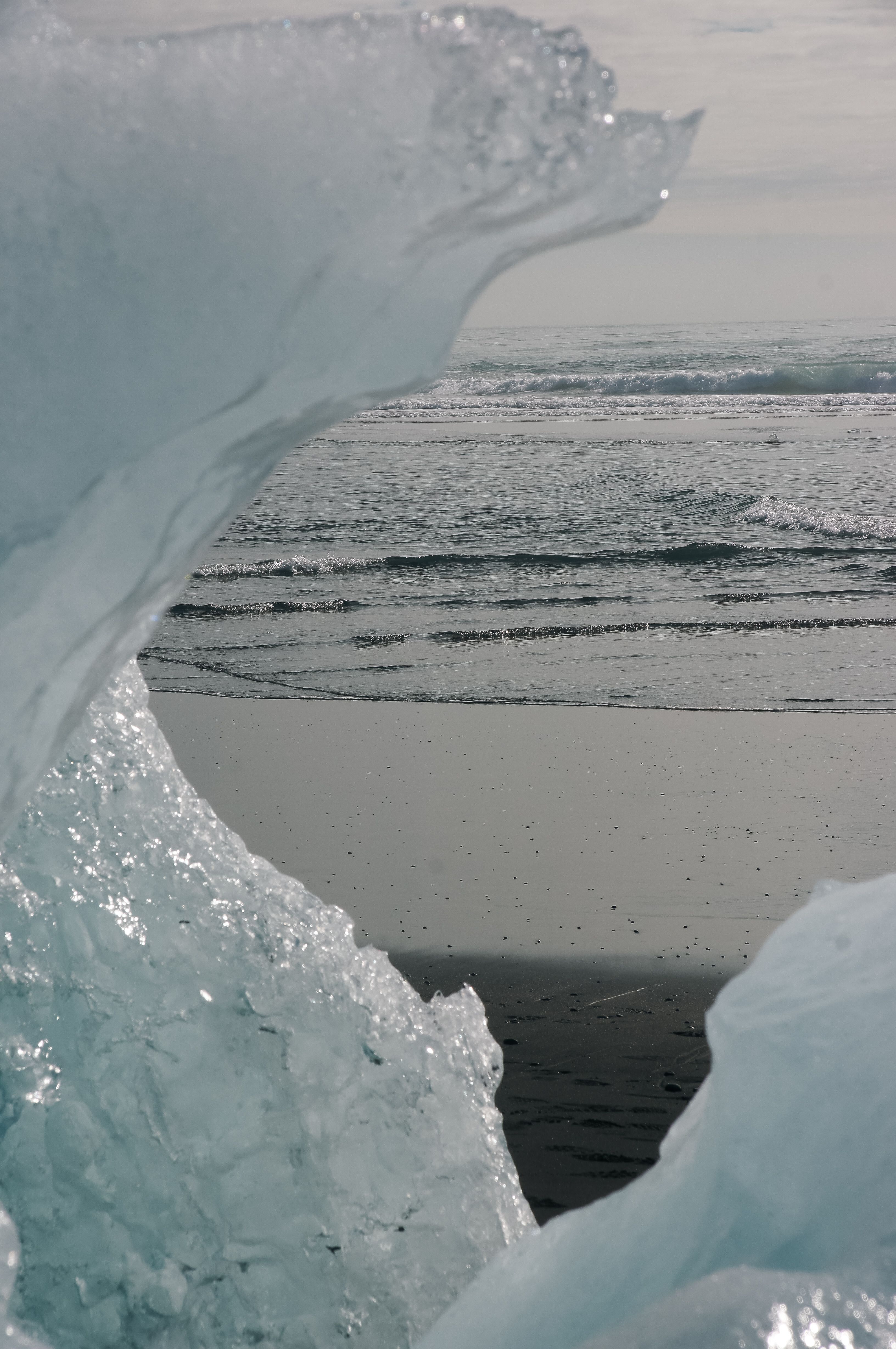 Capture of a tranquil beach with unique ice formations and gentle waves. Ideal for winter and nature themes.