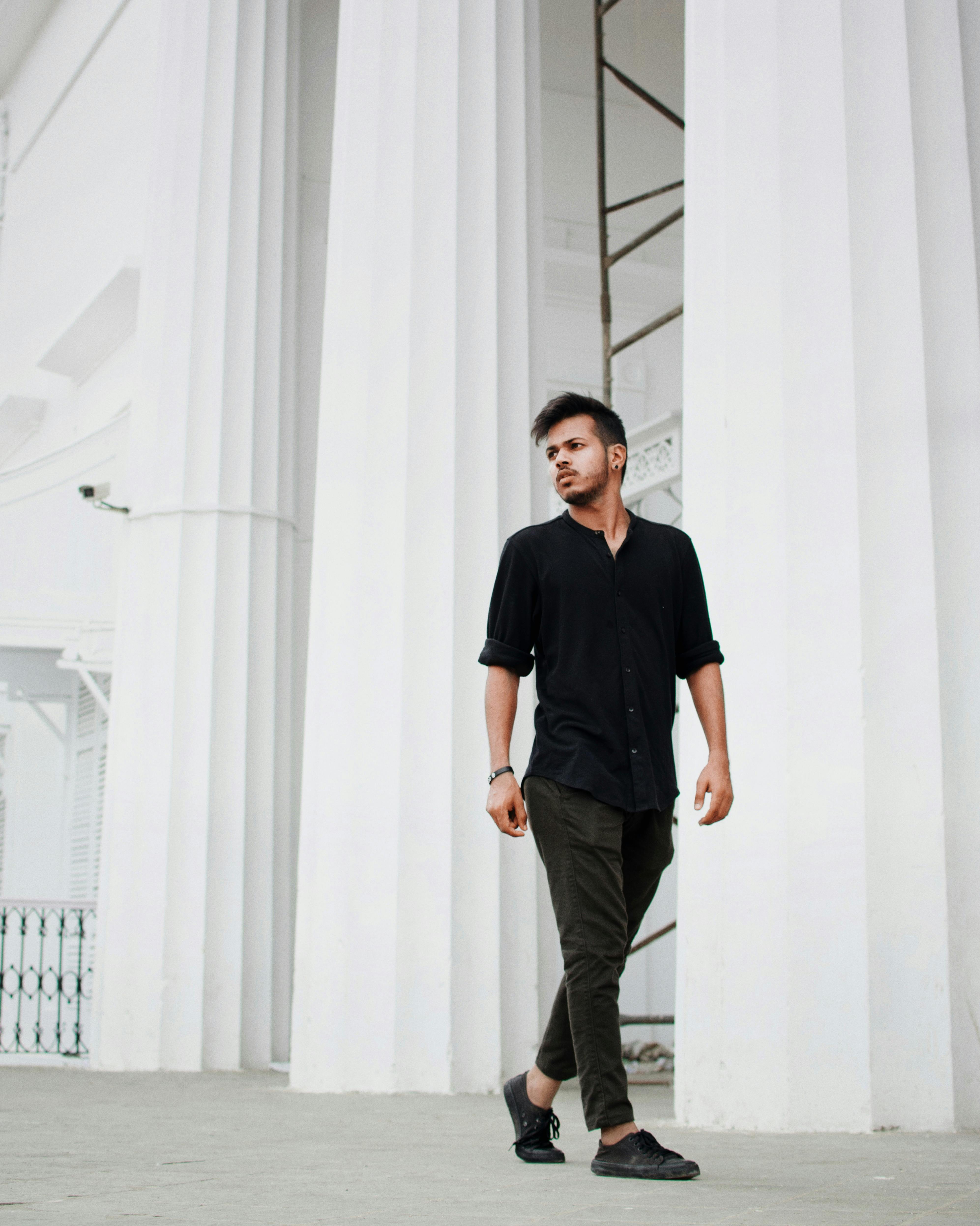 一位穿着休闲服装的时尚男子自信地走在白色大柱上