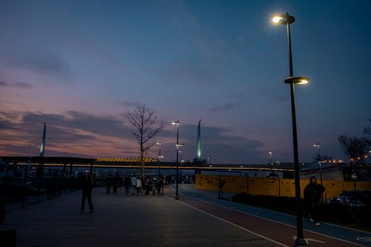 People Walking along a Promenade at Dusk