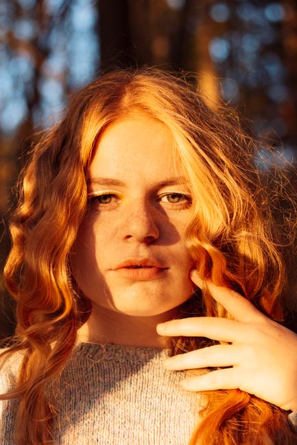 A captivating portrait of a redhead woman in sunlight, showcasing her long hair and natural beauty.