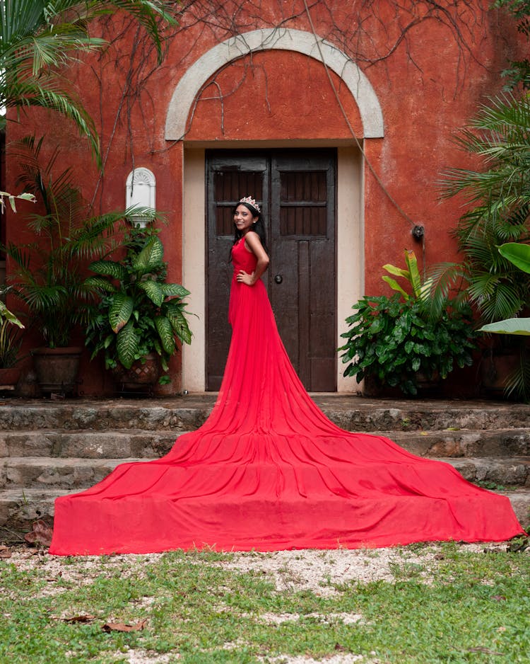 Woman Wearing Red Dress And Crown In Front Of A Building 