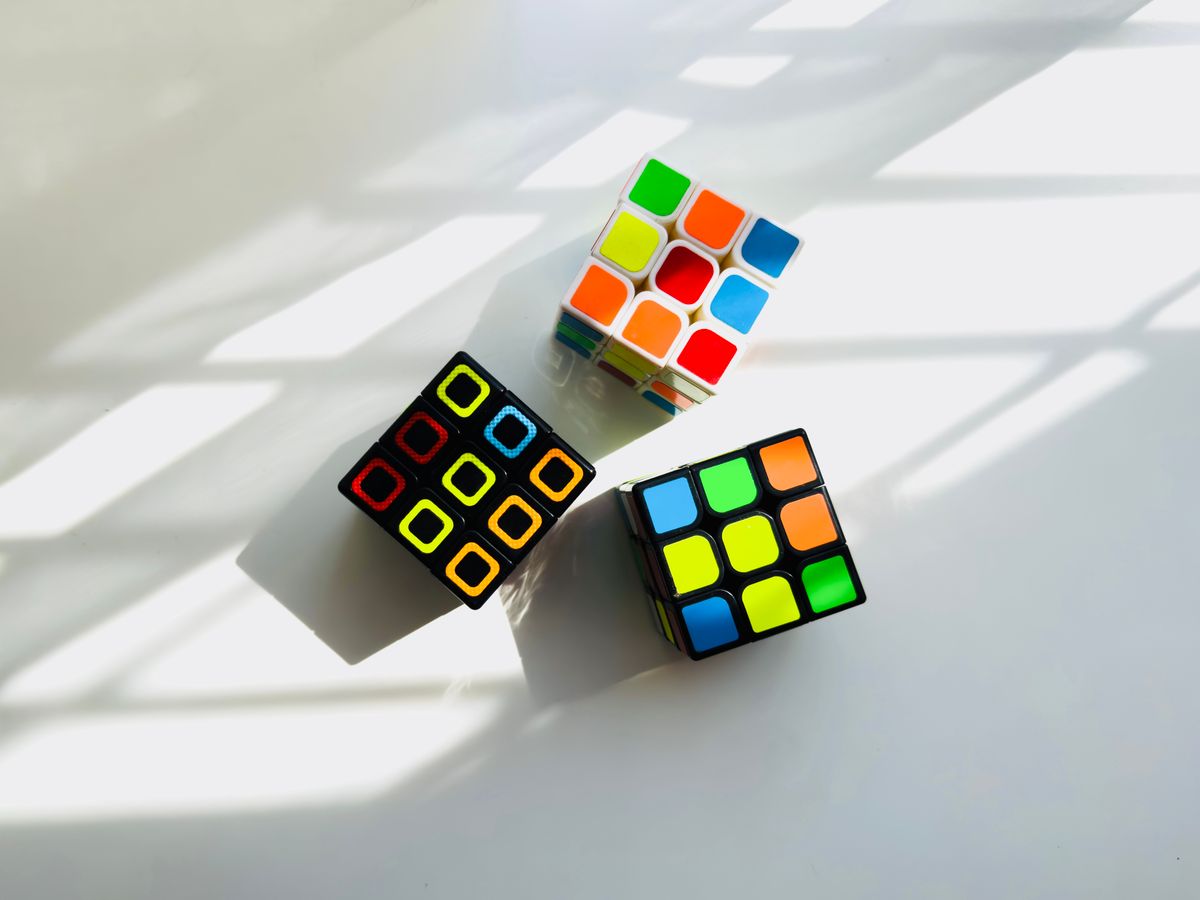 three colorful 3x3 cubes arranged on a light surface