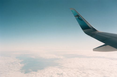 A wing of an airplane flying over the clouds