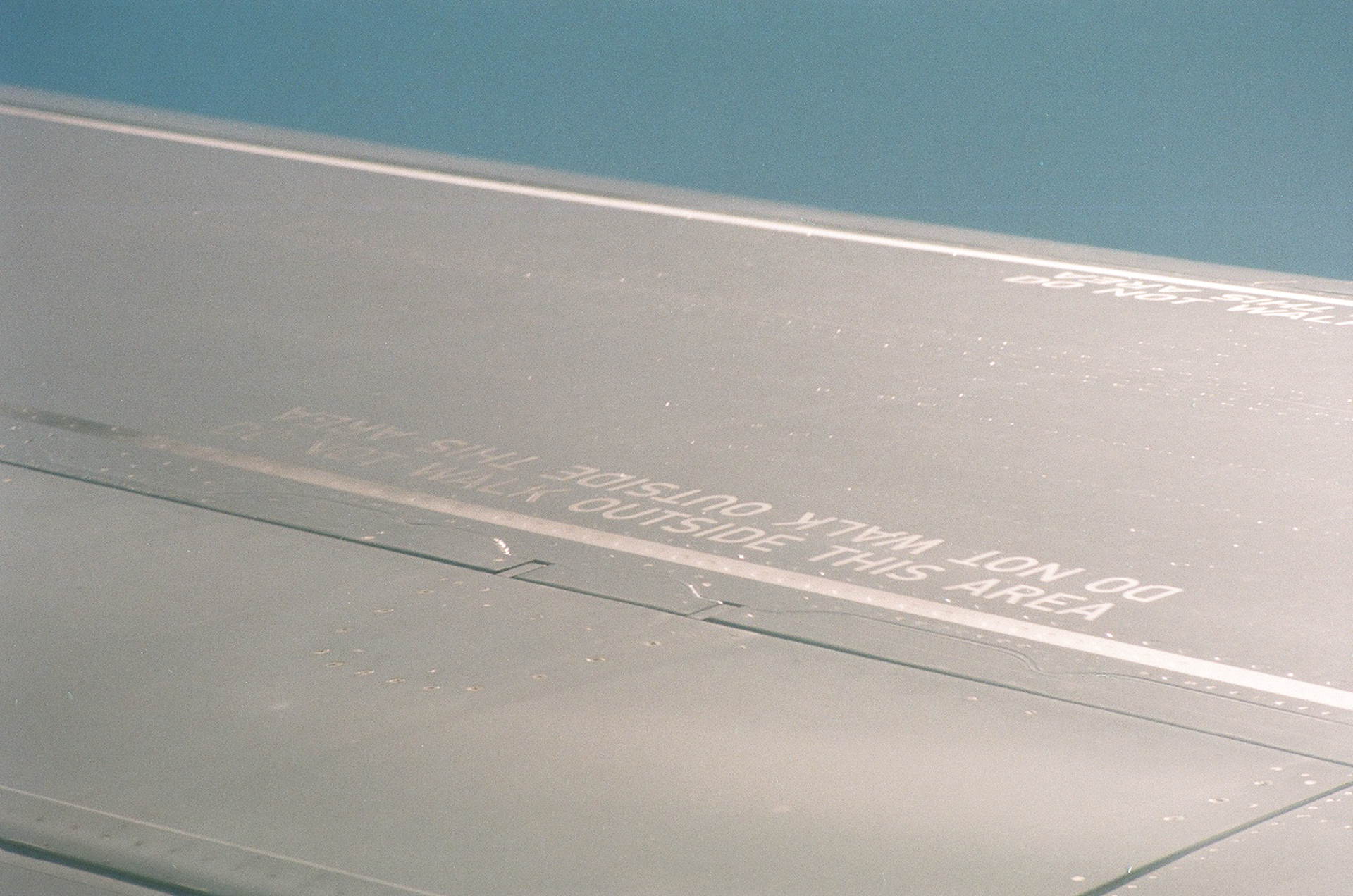 Close-up of an airplane wing with visible safety warnings and text.