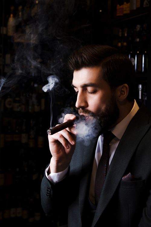 Free Portrait of an elegant man smoking a cigar with a sophisticated ambiance in a New York City bar. Stock Photo