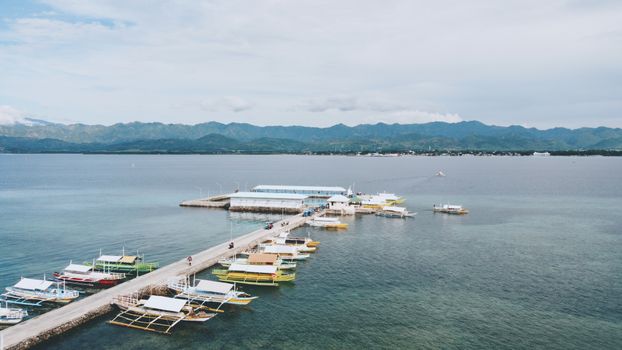 Aerial shot of traditional fishing boats docked at San Carlos City, Philippines harbor, with mountain backdrop.