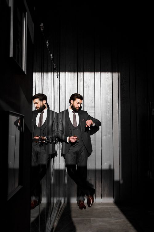 Free Elegant businessman in New York City looks at his watch, reflecting in a modern urban wall. Stock Photo