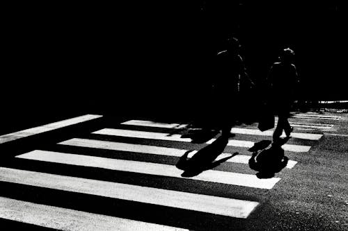 Silhouettes of People Walking on Crossing