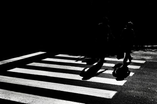 Free High contrast black and white image of people walking across a street in silhouette at night. Stock Photo