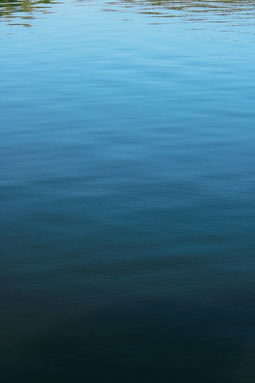 Free Calm and serene blue water surface with gentle ripples. Ideal for backgrounds. Stock Photo
