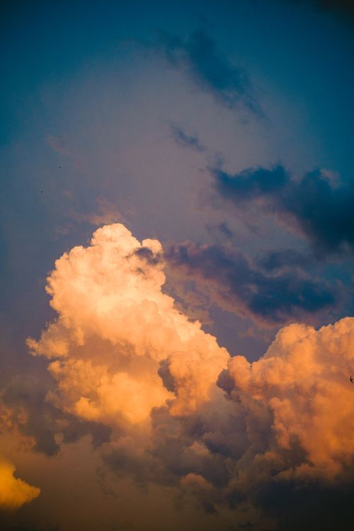 Free A dramatic sky with vibrant clouds illuminated by a golden sunset, showcasing stunning color contrasts. Stock Photo