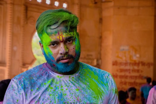 A man covered in bright colors participates in a Holi festival celebration.